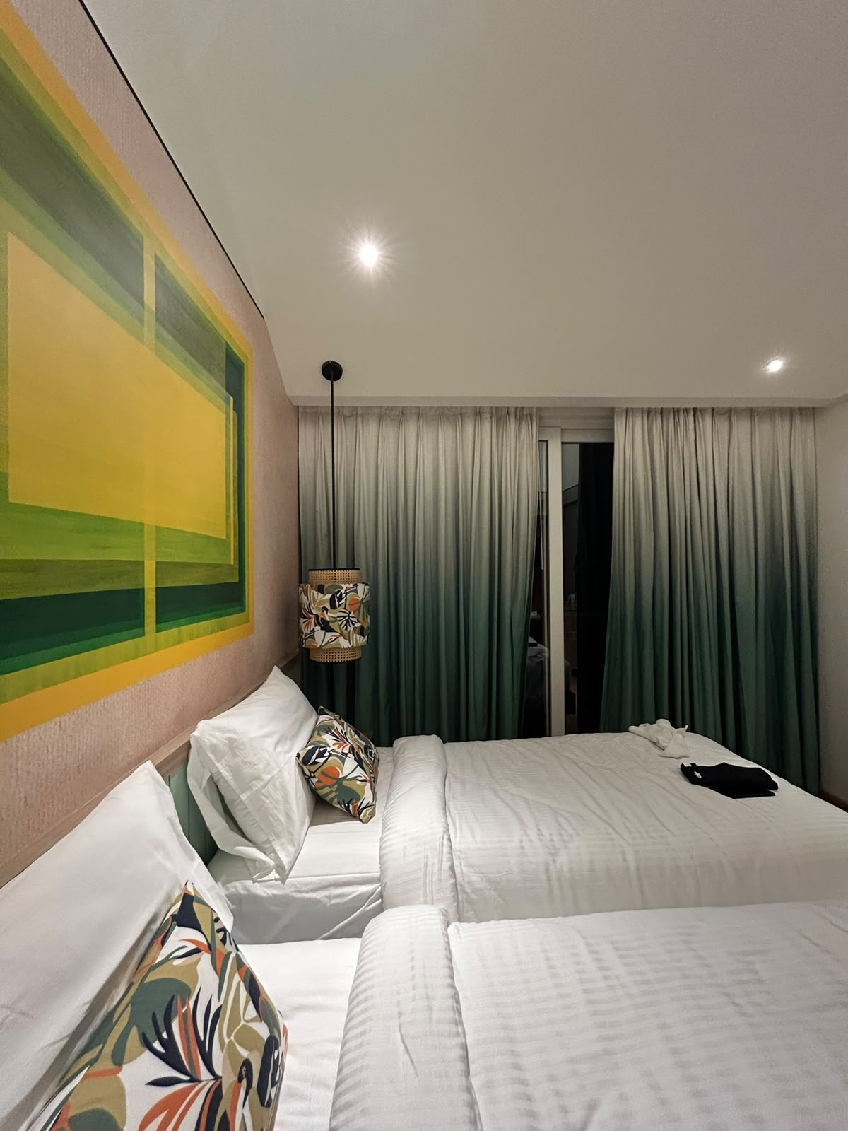 Twin beds in a modern hotel room with tropical leaf pillows at Ibis Goa