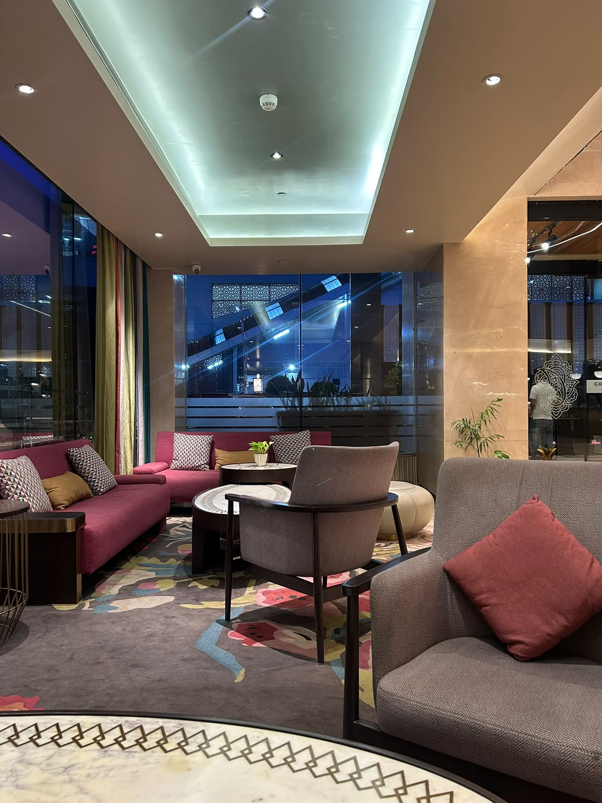 Lounge at Accor Grand Mercure Agra with magenta sofa and grey armchairs at night
