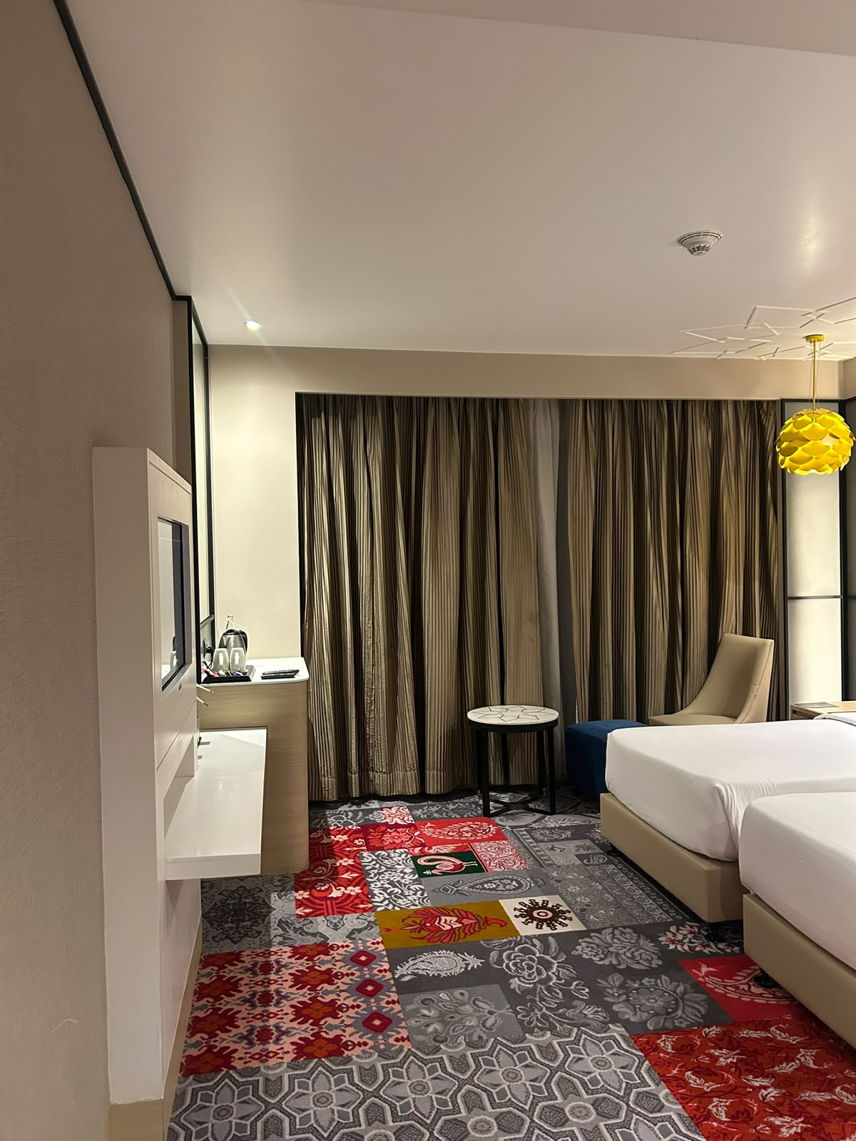 Hotel room with colorful patchwork carpet and yellow pendant light at ITC Andaman