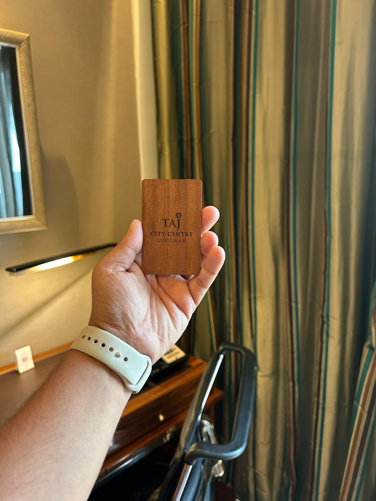 Wooden Taj City Centre Gurugram hotel key card held in hand